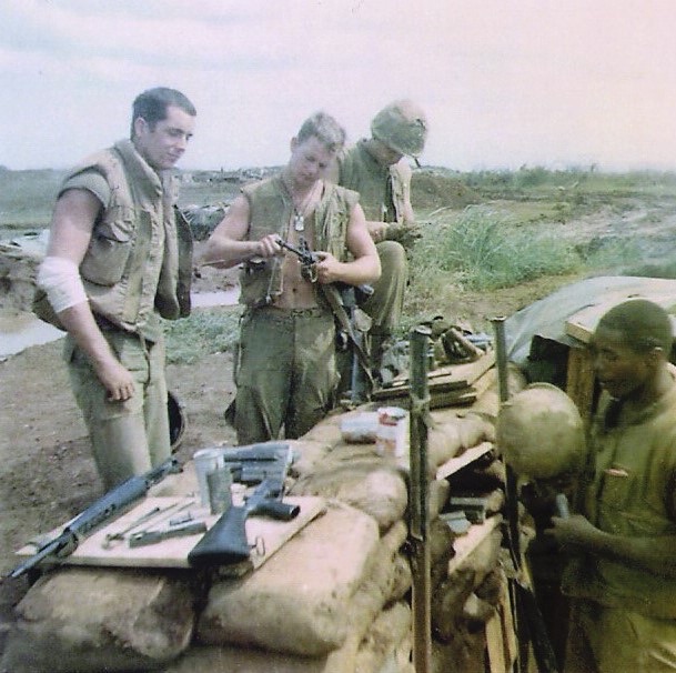 Marines cleaning their weapons at a sandbagged position